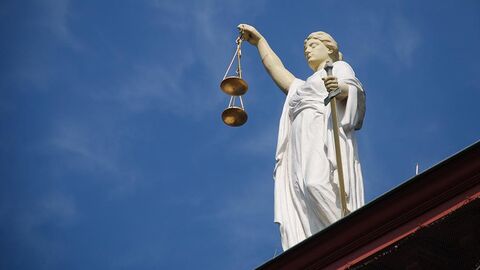 Weiße Justitia-Statue steht auf einem Dach.